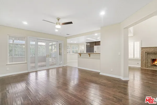 a view of an empty room with wooden floor and a kitchen