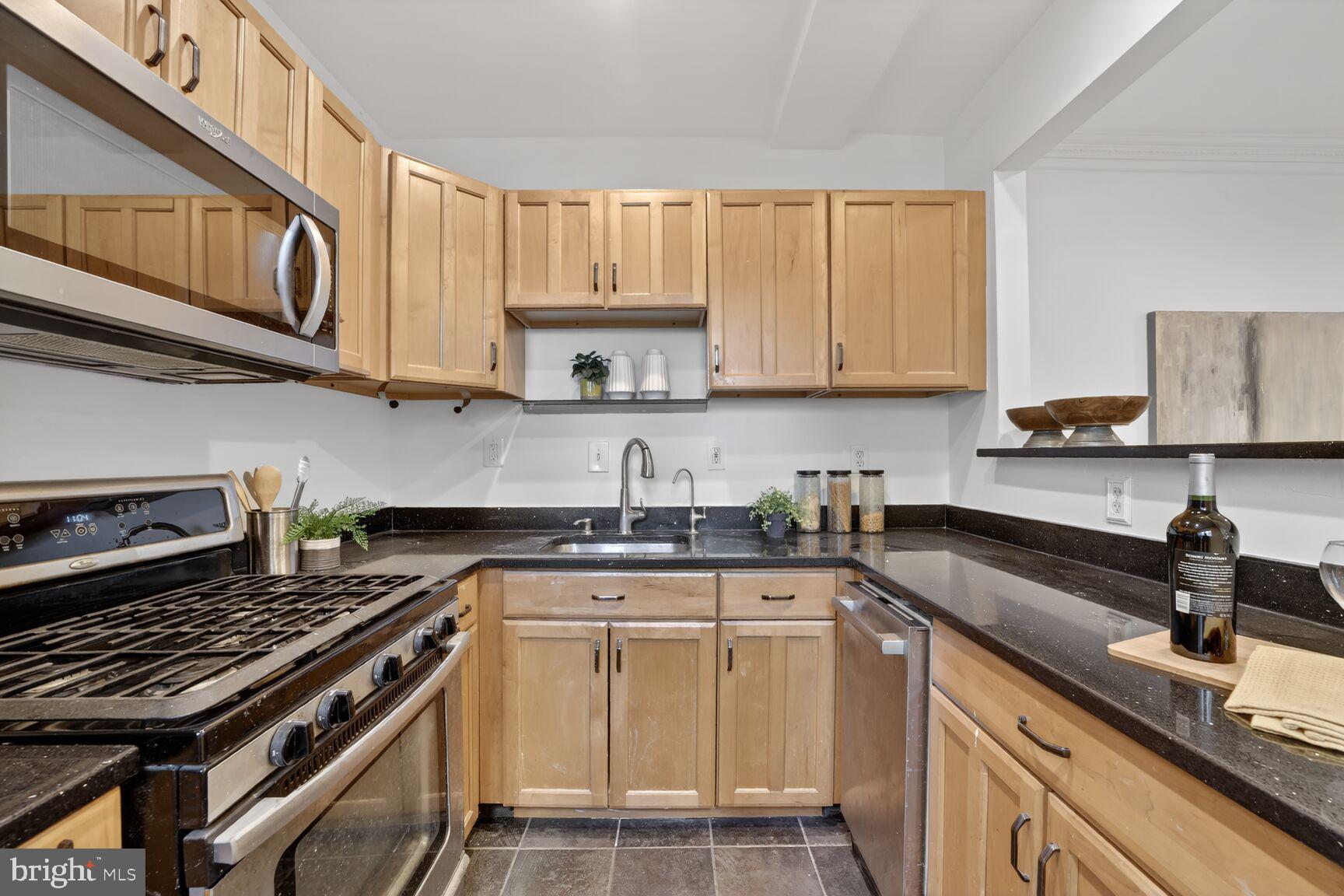 1669 Columbia Road Northwest, Unit 313 Washington, DC 20009 - Photo 14 of 20 a kitchen with stainless steel appliances granite countertop a stove a sink dishwasher and cabinets with wooden floor