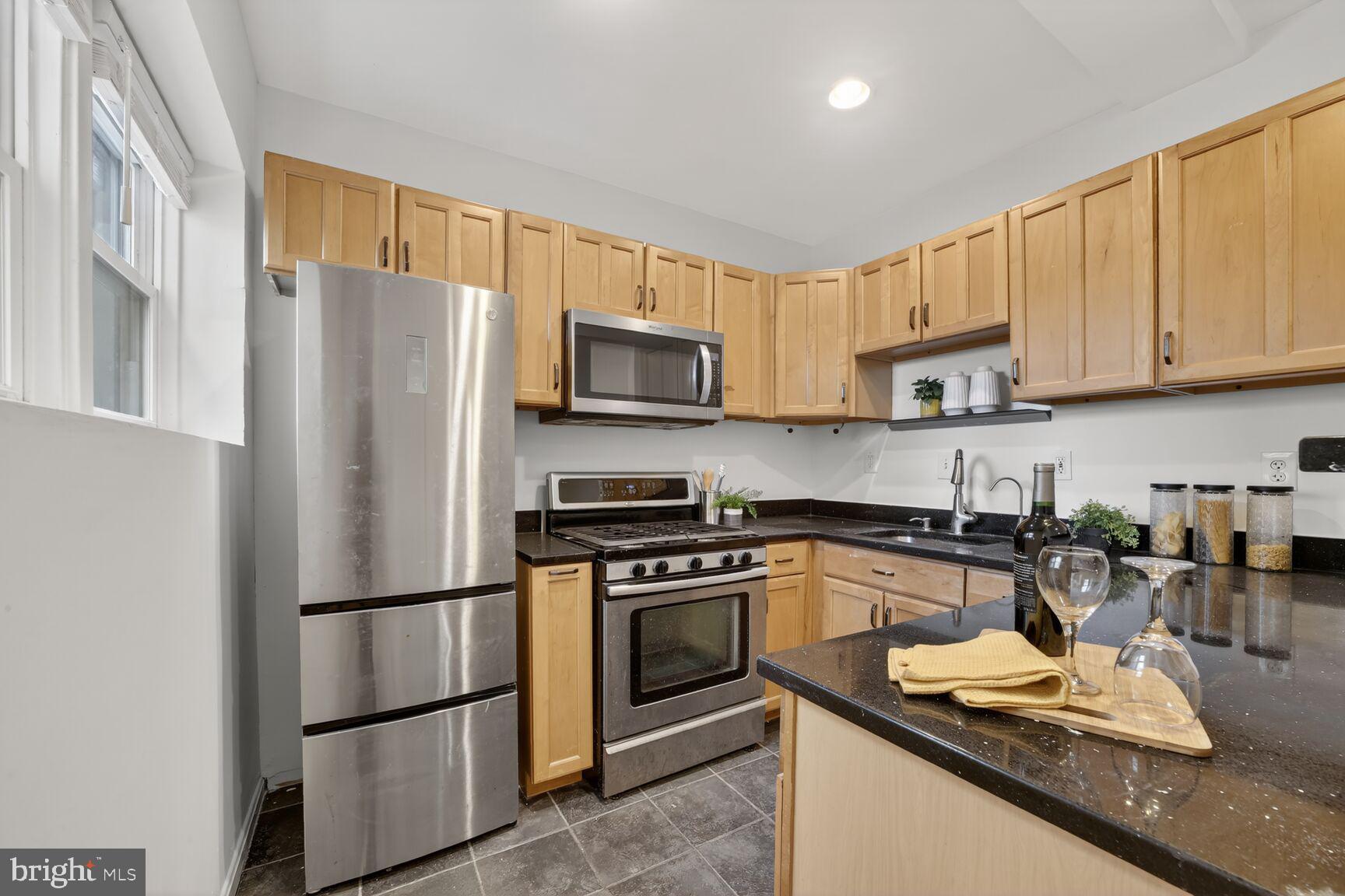 1669 Columbia Road Northwest, Unit 313 Washington, DC 20009 - Photo 15 of 20 a kitchen with granite countertop a refrigerator stove and microwave