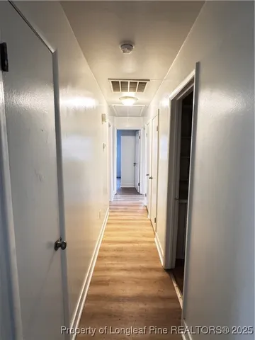 a view of a hallway with wooden floor and closet