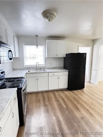 a kitchen with a sink a refrigerator a window and cabinets