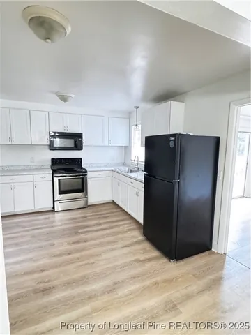 a kitchen with granite countertop a refrigerator and a stove top oven