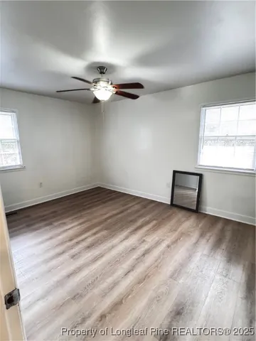 an empty room with windows and ceiling fan