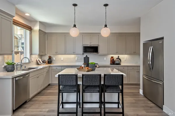 a kitchen with a dining table chairs refrigerator and microwave