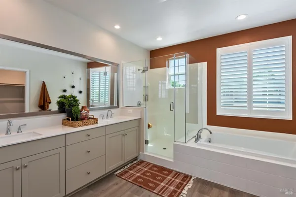 a bathroom with a double vanity sink large mirror and a bathtub