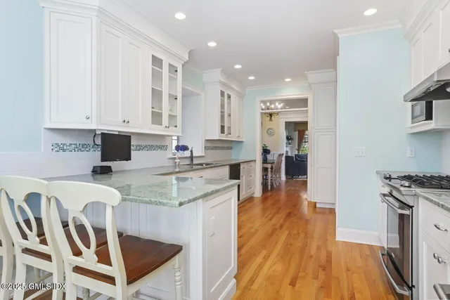 a kitchen with granite countertop white cabinets and stainless steel appliances