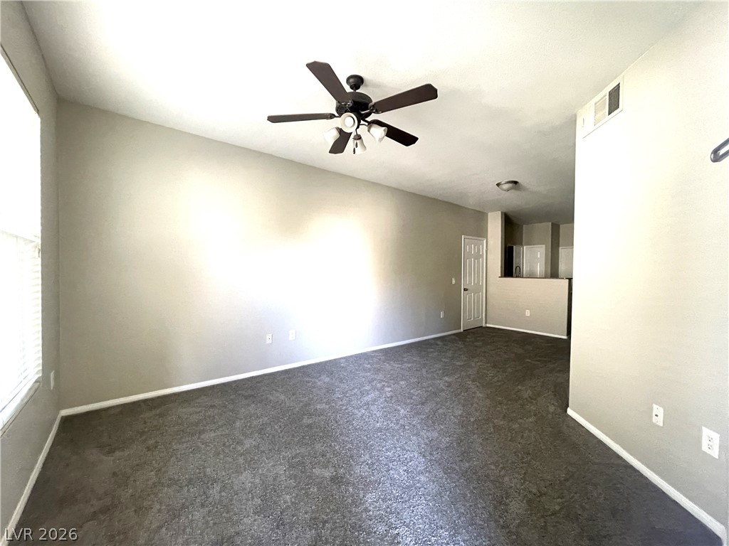 10001 Peace Way, Unit 1327 Las Vegas, NV 89147 - Photo 5 of 21 A versatile living space with plush carpeting and a modern ceiling fan, ready for your personal touch.