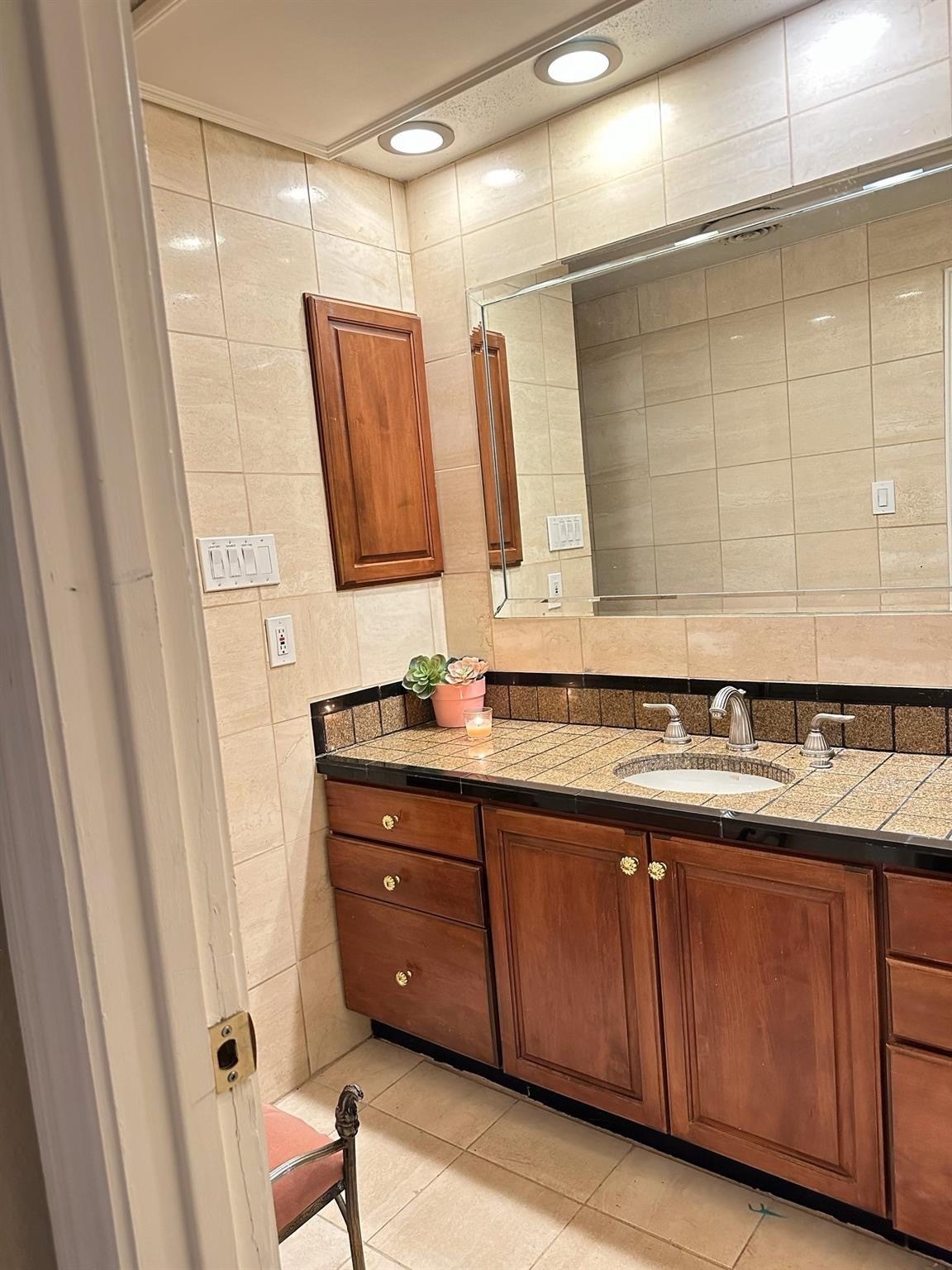 2100 Tanglewilde Street, Unit 537 Houston, TX 77063 - Photo 11 of 13 a bathroom with a granite countertop sink and a mirror