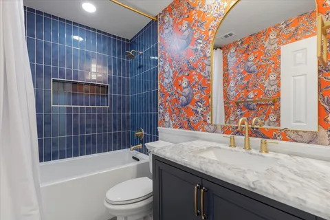 a bathroom with a granite countertop bathtub sink vanity mirror and toilet