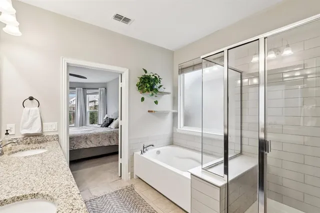 a bathroom with a tub shower and bedroom view