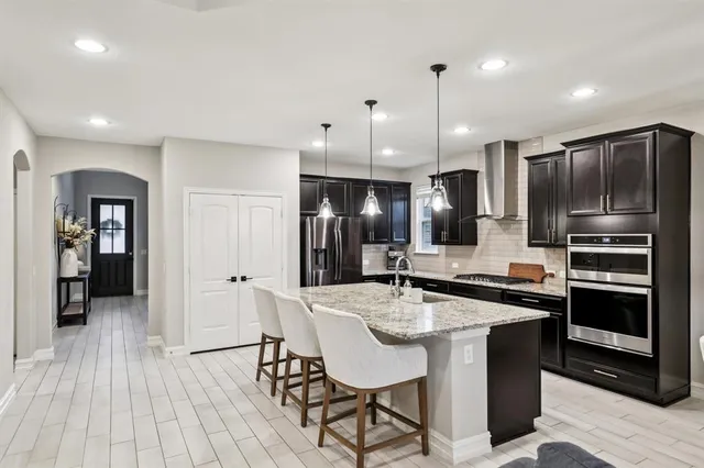 a kitchen with stainless steel appliances kitchen island granite countertop a kitchen island a hardwood floor and a sink