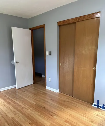 a view of an empty room with wooden floor and a bathroom