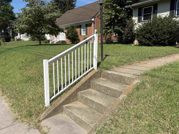 a view of a house with a small yard and a large tree