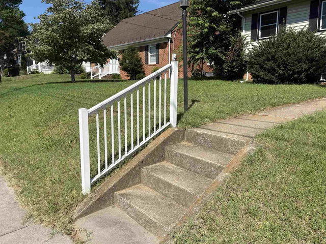 a view of a house with a small yard and a large tree