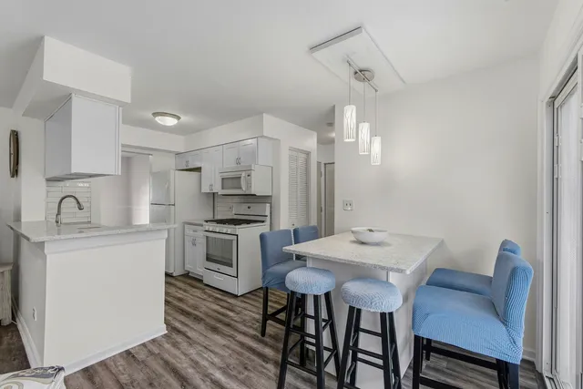 a kitchen with stainless steel appliances kitchen island a table chairs and a refrigerator