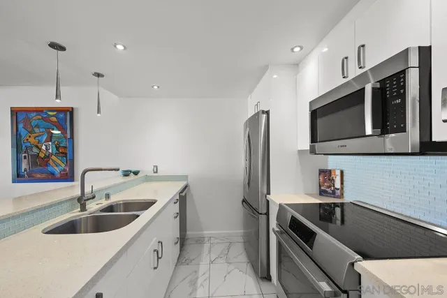 a kitchen with stainless steel appliances granite countertop a sink and a refrigerator