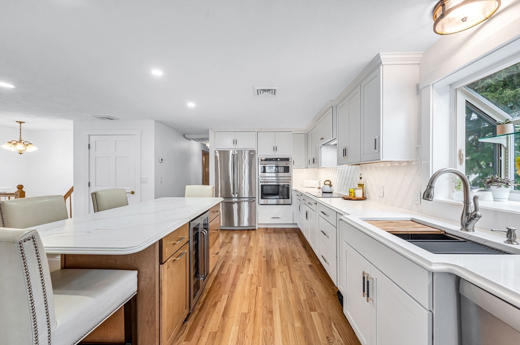 83 Loomis Drive Chicopee, MA 01020 - Photo 5 of 40 a large kitchen with kitchen island a stove a sink a refrigerator and white cabinets with wooden floor
