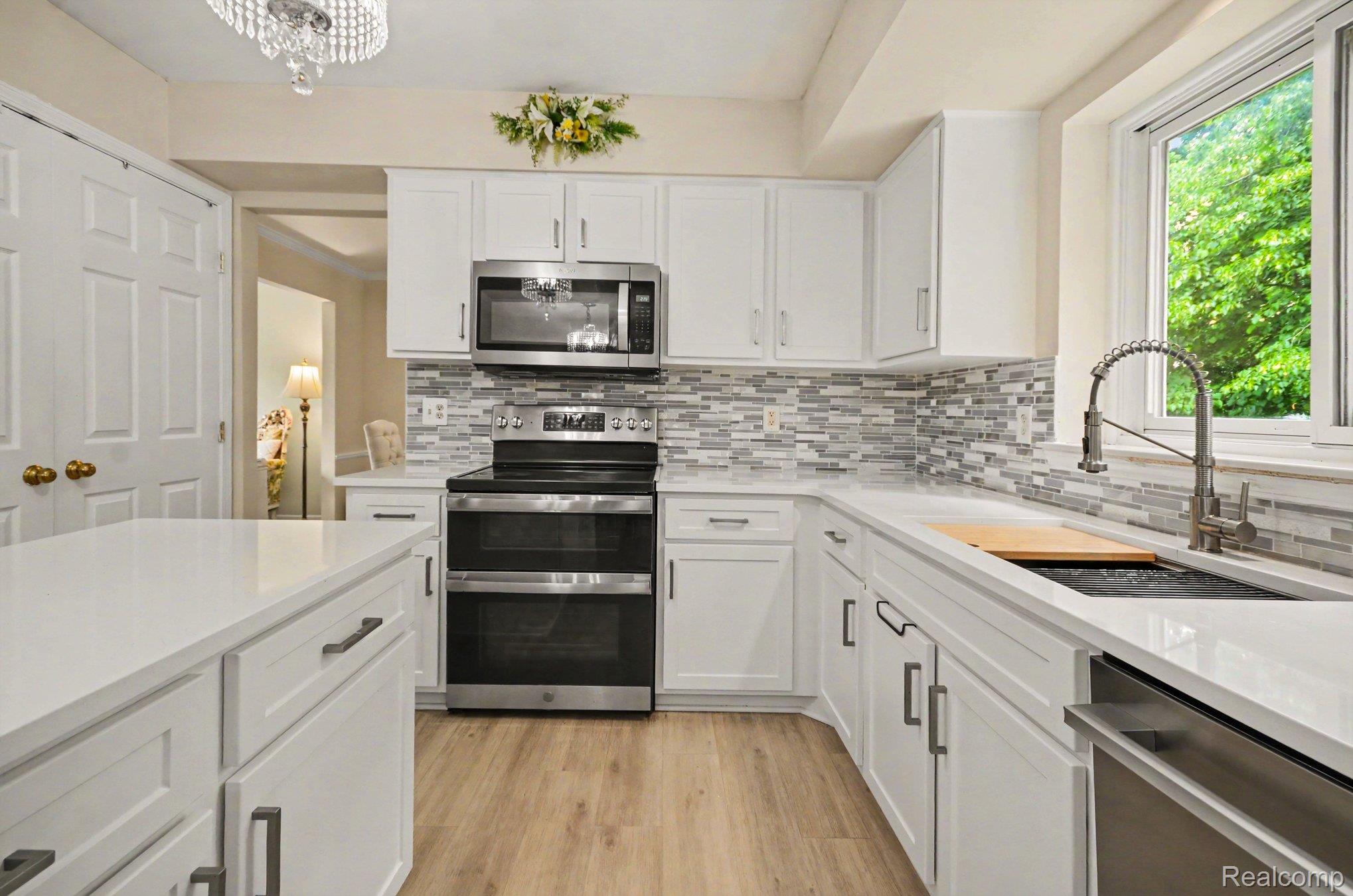425 Thornridge Court Rochester, MI 48307 - Photo 4 of 35 Modern kitchen featuring white cabinetry, light countertops, wood-finish flooring, a stainless steel double oven range, and a mosaic tile backsplash