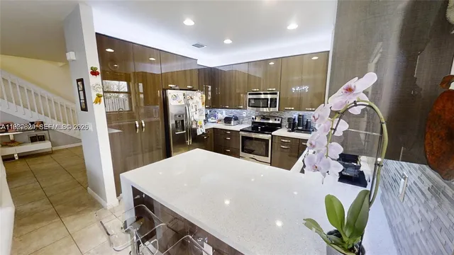 a kitchen with stainless steel appliances kitchen island granite countertop a stove a refrigerator a sink a oven with a dining table and chairs