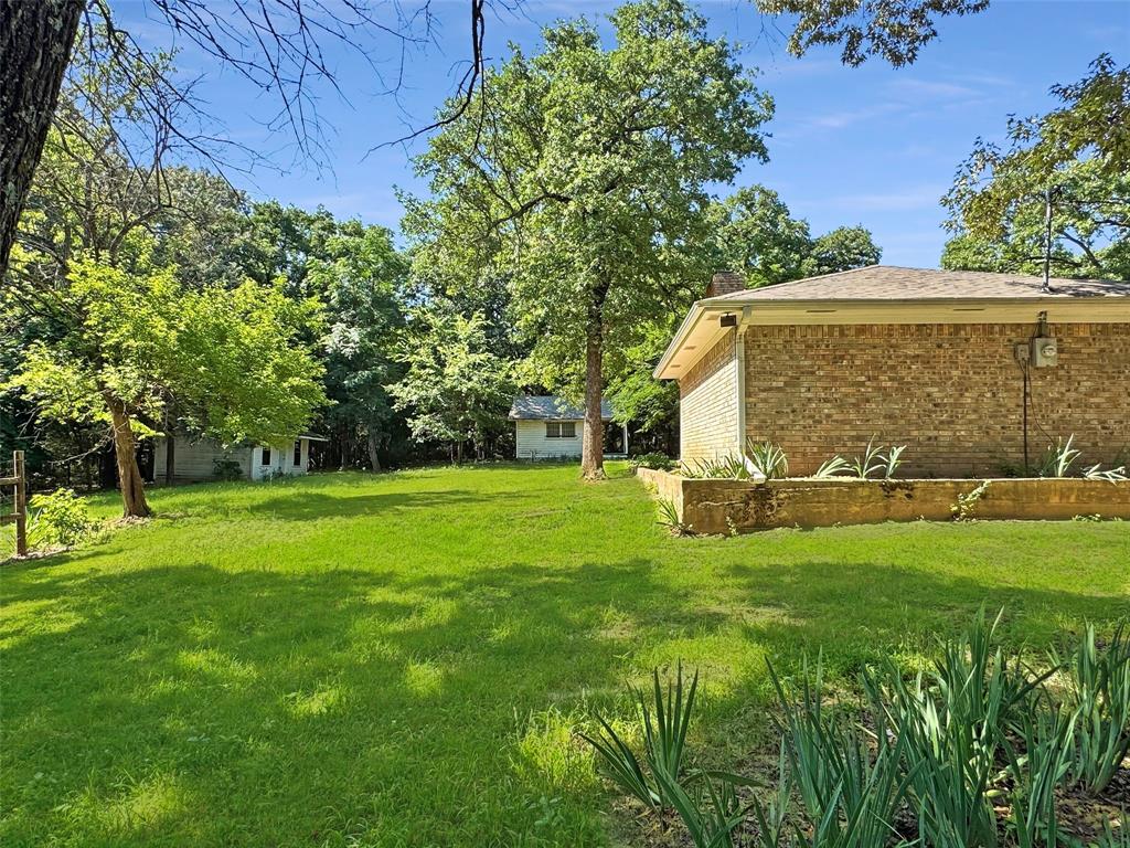 3870 County Road Arthur City, TX 75411 - Photo 4 of 39 Expansive green lawn with mature trees and a brick-sided exterior