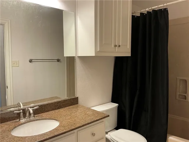 a bathroom with a granite countertop sink toilet and a mirror