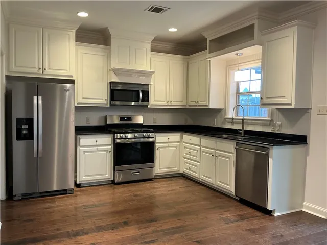 a kitchen with granite countertop a sink stainless steel appliances and window