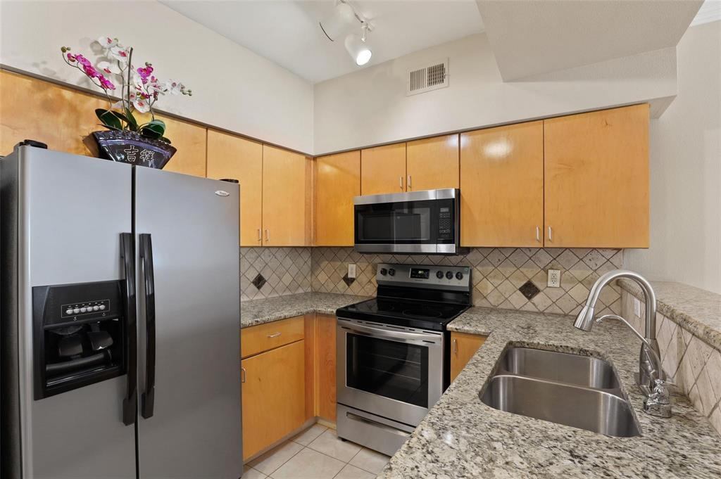 3102 Kings Road, Unit 1303 Dallas, TX 75219 - Photo 4 of 25 a kitchen with stainless steel appliances a sink cabinets and a refrigerator