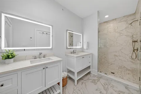 a spacious bathroom with double sink shower and a mirror