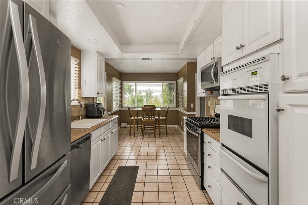 7233 Bel Air Street Corona, CA 92881 - Photo 23 of 39 a kitchen with stainless steel appliances a table chairs and a refrigerator
