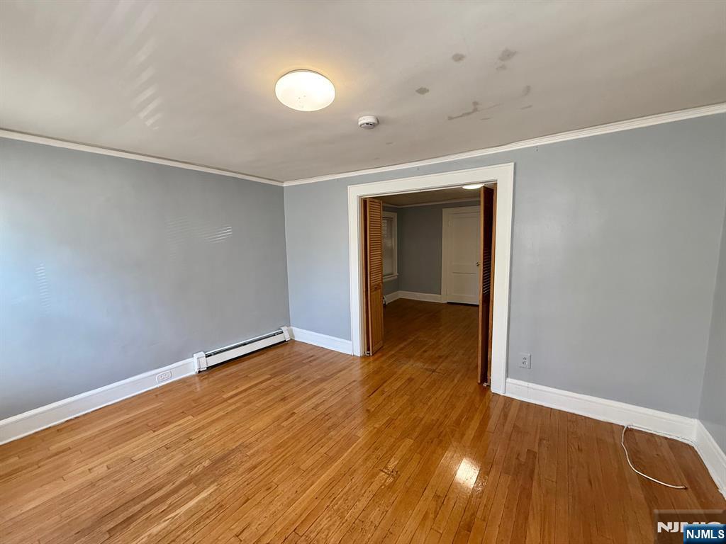 122 Cross Street, Unit 1 Harrison, NJ 07029 - Photo 5 of 10 a view of an empty room with wooden floor and a window