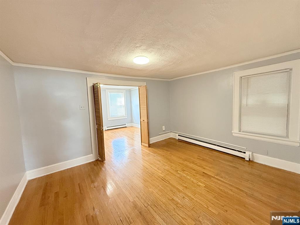 122 Cross Street, Unit 1 Harrison, NJ 07029 - Photo 8 of 10 an empty room with wooden floor and windows