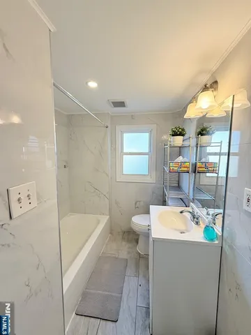 a bathroom with a tub a sink a mirror and a shower