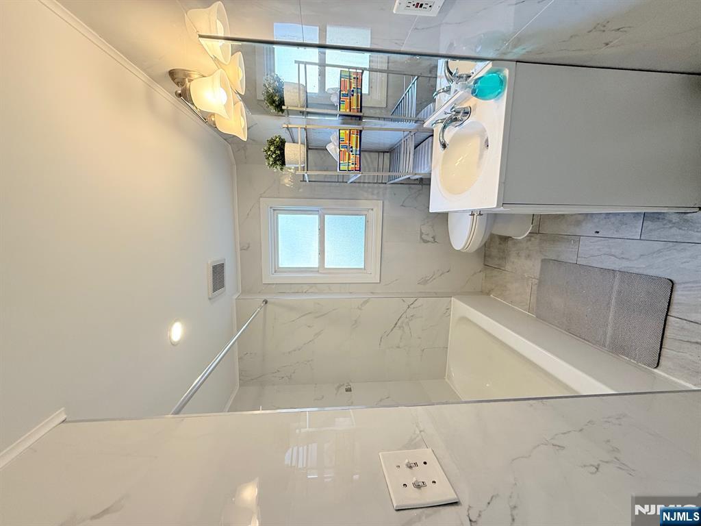 122 Cross Street, Unit 1 Harrison, NJ 07029 - Photo 9 of 10 a bathroom with a tub a sink a mirror and a shower