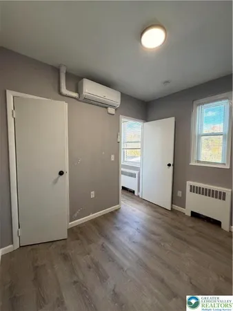 an empty room with wooden floor cabinet and windows