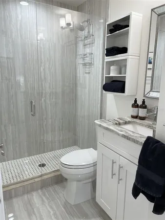 a bathroom with a granite countertop sink toilet and shower