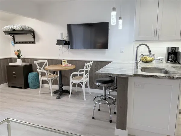 a kitchen with stainless steel appliances granite countertop a stove top oven a sink a dining table and chairs with wooden floor