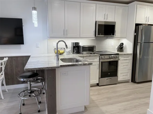 a kitchen with stainless steel appliances a stove a sink a microwave and refrigerator