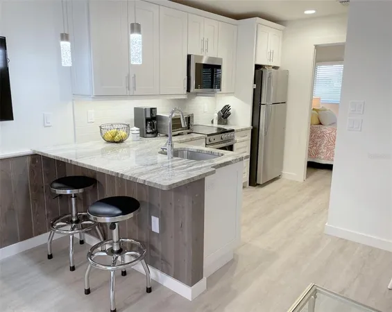 a kitchen with stainless steel appliances a sink a stove a refrigerator cabinets and dining table