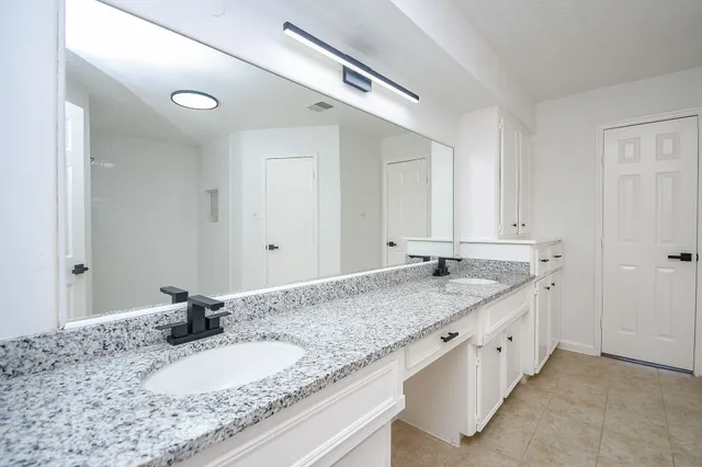 a bathroom with a granite countertop double vanity sink and mirror