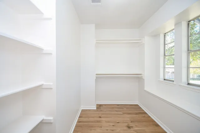 a view of empty room with wooden floor and window