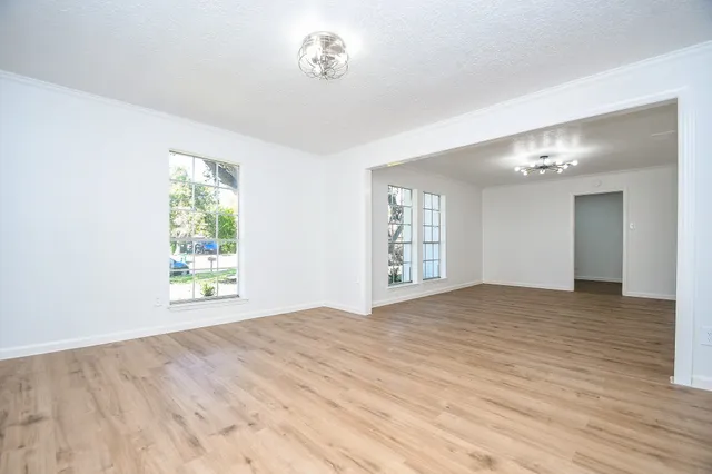 a view of an empty room with a window and wooden floor