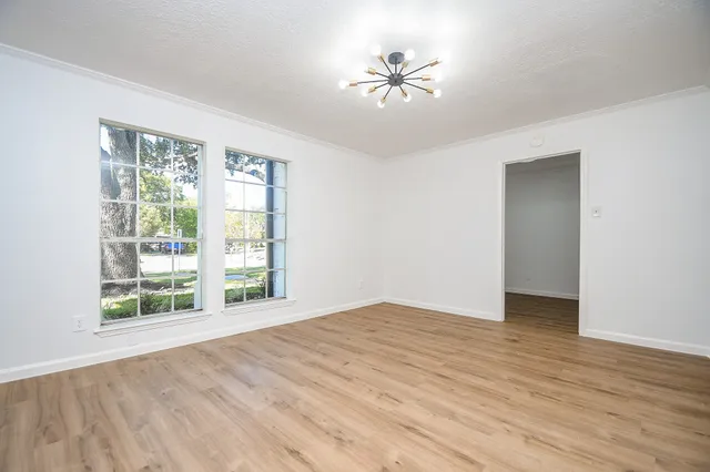 a view of an empty room with a window and wooden floor