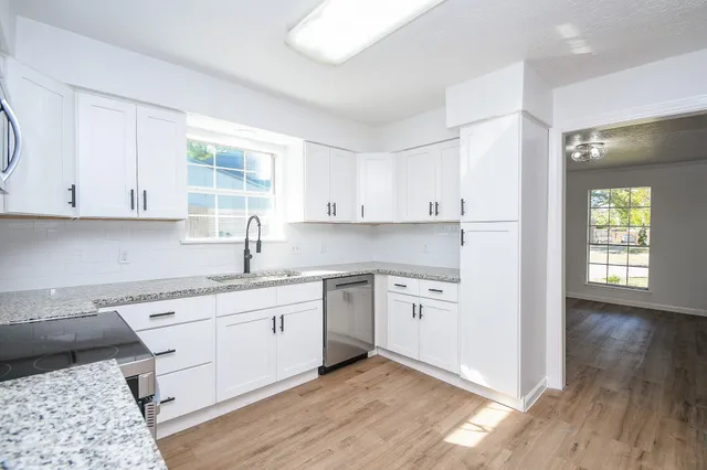 a kitchen with granite countertop white cabinets and white appliances