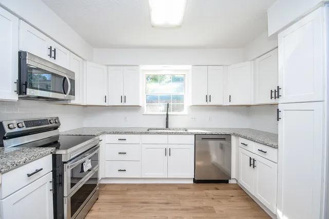 a kitchen with white cabinets stainless steel appliances and a window