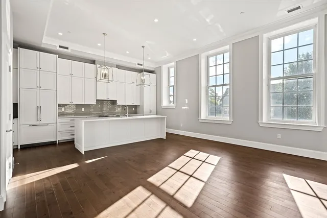 a large white kitchen with wooden floor and a window