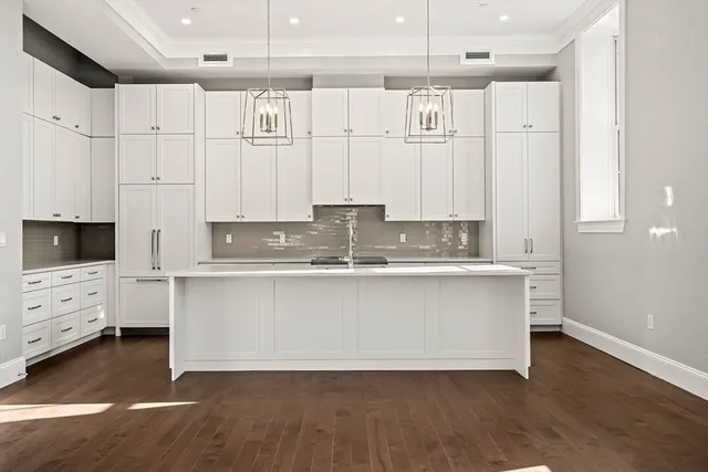 a white kitchen with granite countertop a stove a sink and white cabinets