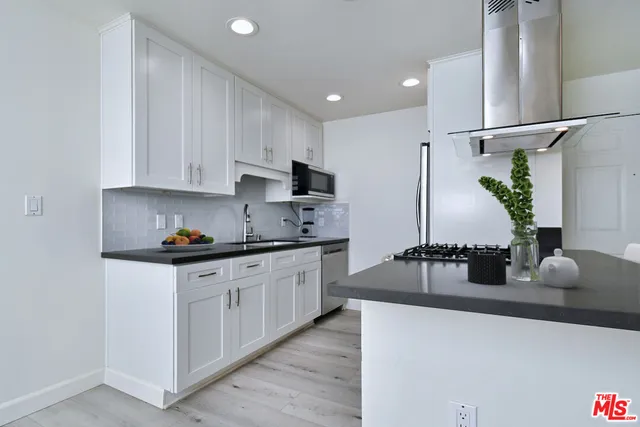 a kitchen with granite countertop a sink cabinets and stainless steel appliances