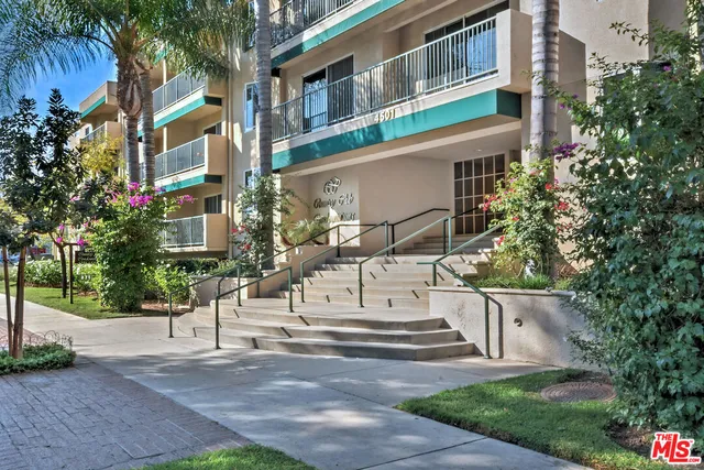 a view of a white building among the street with palm trees