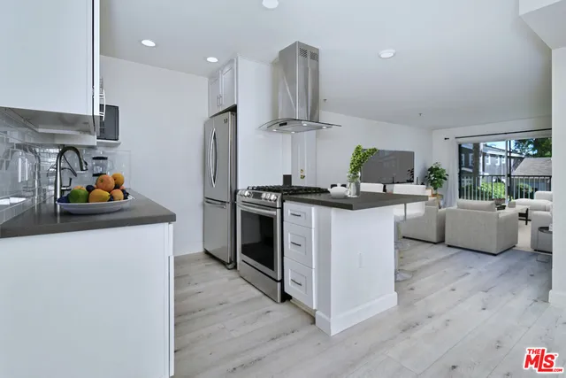 a kitchen with stainless steel appliances a sink wooden floor and a refrigerator