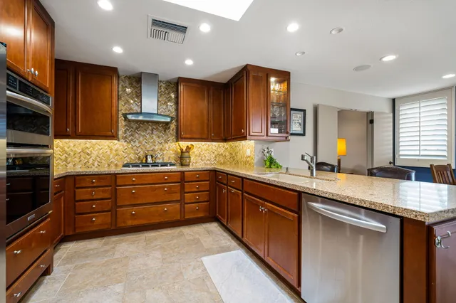 a kitchen with stainless steel appliances granite countertop a refrigerator a stove and a sink